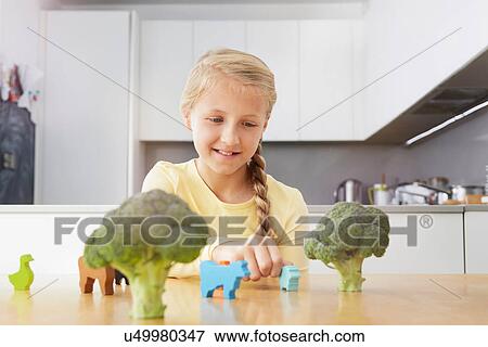Girl playing with toy animals around broccoli View Large Photo Image Stock Photo - Girl playing with toy animals around broccoli. Fotosearch