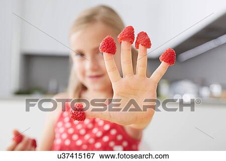 Stock Photo - Girl putting raspberries on fingers. Fotosearch