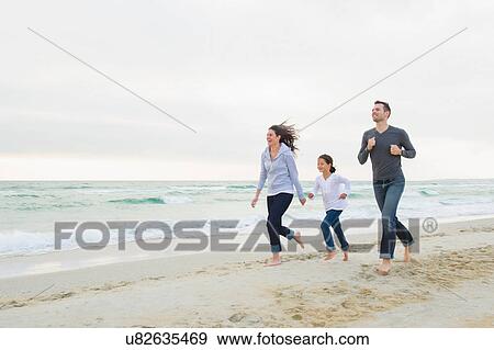 Girl running along beach with mother and father View Large Photo Image Stock Photo - Girl running along beach with mother and father. Fotosearch