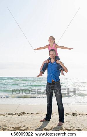 Girl sitting on father's shoulders with arms wide View Large Photo Image Stock Image - Girl sitting on father's shoulders with arms wide. Fotosearch