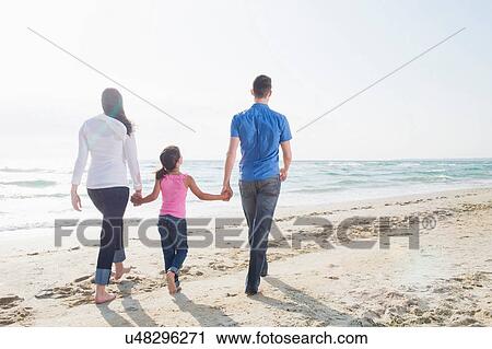 Girl walking along beach with mother and father View Large Photo Image Stock Image - Girl walking along beach with mother and father. Fotosearch