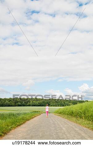 Picture - Girl walking down country road. Fotosearch