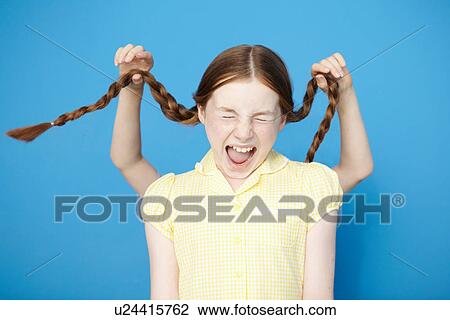 Stock Image - Girl wearing yellow school dress, boy behind pulling her plaits. Fotosearch