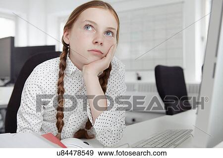 Girl with hand on chin looking up in office View Large Photo Image Stock Photo - Girl with hand on chin looking up in office. Fotosearch