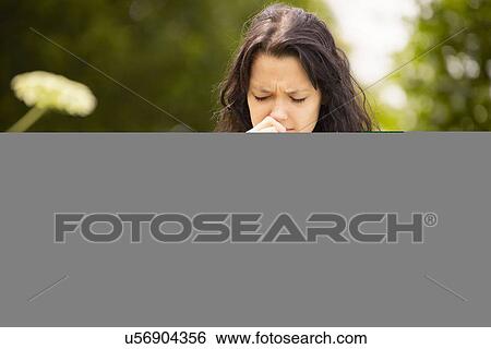 Stock Photograph - Girl with tissue rubbing nose. Fotosearch
