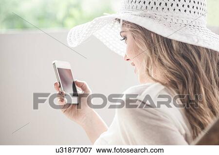 Glamorous young woman in sun hat, using cellphone View Large Photo Image Stock Photo - Glamorous young woman in sun hat, using cellphone. Fotosearch