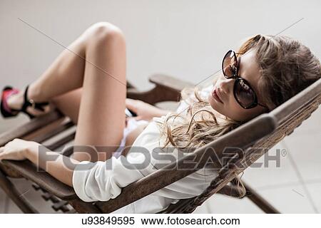 Glamorous young woman reclining on chair View Large Photo Image Stock Photography - Glamorous young woman reclining on chair. Fotosearch