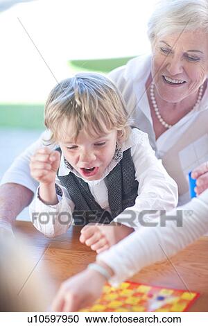 Stock Image - Gran playing board game with grandchildren. Fotosearch