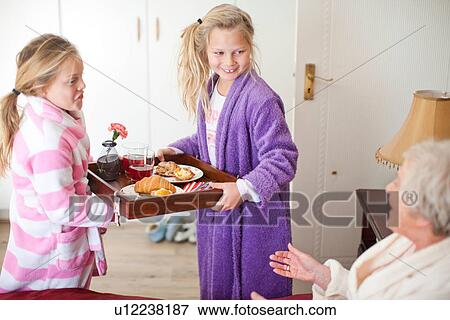 Stock Photo - Granddaughters giving grandmother breakfast in bed. Fotosearch