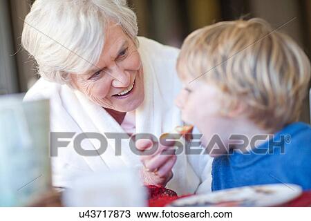 Grandmother feeding grandson breakfast View Large Photo Image Stock Image - Grandmother feeding grandson breakfast. Fotosearch