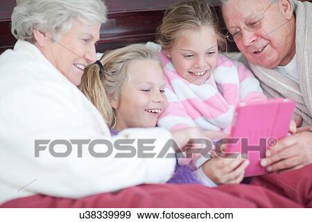 Grandparents and grandchildren playing digital game in bed View Large Photo Image Stock Photo - Grandparents and grandchildren playing digital game in bed. Fotosearch