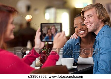 Stock Image - Group of friends in cafe with digital tablet. Fotosearch