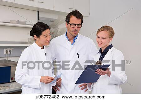 Group of scientists checking clipboard View Large Photo Image Stock Image - Group of scientists checking clipboard. Fotosearch