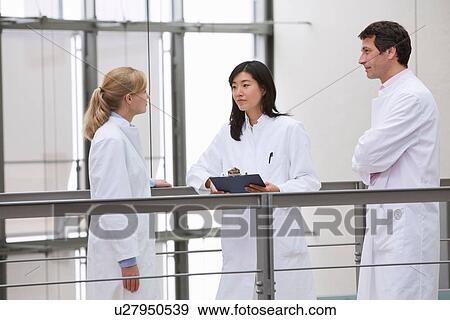 Stock Photo - Group of scientists holding meeting in atrium. Fotosearch