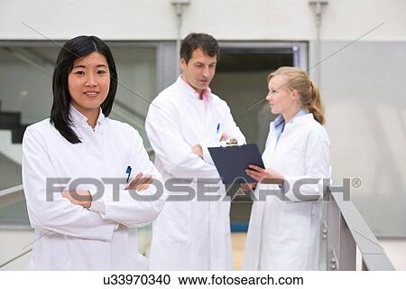 Stock Image - Group of scientists in atrium with clipboard. Fotosearch