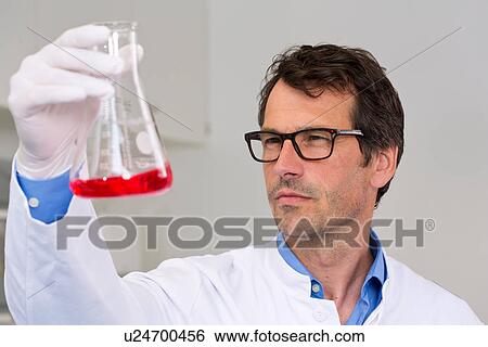 Male scientist examining ph-reaction of liquid in flask View Large Photo Image Stock Photograph - Male scientist examining ph-reaction of liquid in flask. Fotosearch