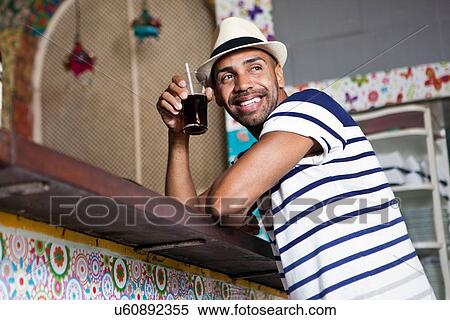 Man at counter of cafe bar, holding a drink View Large Photo Image Stock Photography - Man at counter of cafe bar, holding a drink. Fotosearch