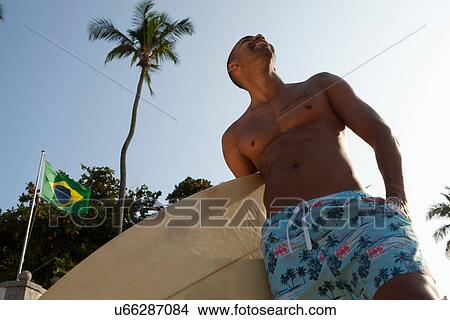 Man holding surfboard, low angle View Large Photo Image Picture - Man holding surfboard, low angle. Fotosearch