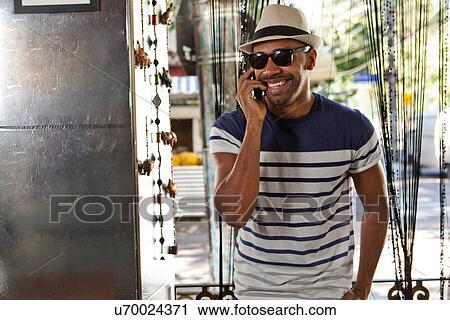 Man in hat and sunglasses, using cellphone View Large Photo Image Stock Image - Man in hat and sunglasses, using cellphone. Fotosearch