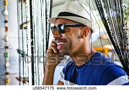 Man in hat and sunglasses, using cellphone View Large Photo Image Stock Photography - Man in hat and sunglasses, using cellphone. Fotosearch