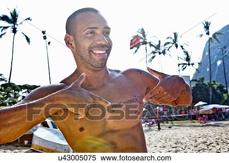 Man on beach pointing to chest with tattoo saying Made In Brazil View Large Photo Image Stock Photography - Man on beach pointing to chest with tattoo saying Made In Brazil. Fotosearch