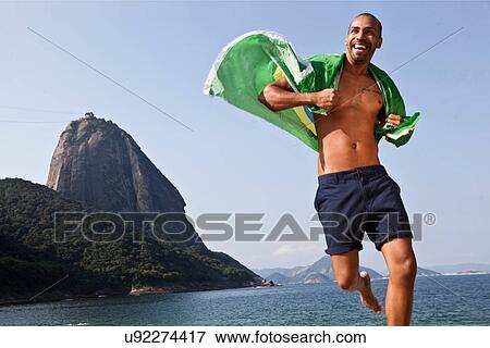 Man running on beach with Brazilian flag, Rio de Janeiro, Brazil View Large Photo Image Stock Photo - Man running on beach with Brazilian flag, Rio de Janeiro, Brazil. Fotosearch