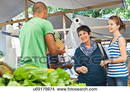 Man selling pineapple to women in market View Large Photo Image Picture - Man selling pineapple to women in market. Fotosearch
