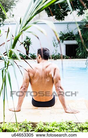 Stock Photography - Man sitting at poolside. Fotosearch