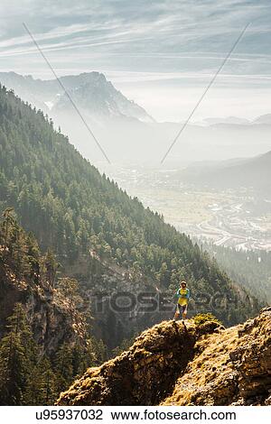 Stock Image - Man standing on mountain, Farchant, Bavaria, Germany. Fotosearch