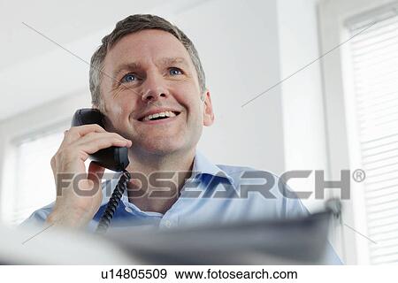 Stock Photo - Mature businessman on landline phone. Fotosearch