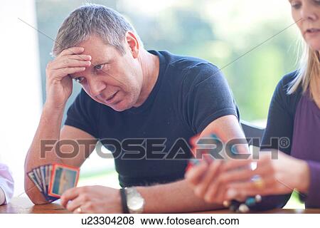 Stock Photo - Mature male playing cards with family. Fotosearch