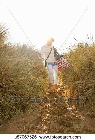 Mature woman walking down sand dunes with beach bag View Large Photo Image Stock Photograph - Mature woman walking down sand dunes with beach bag. Fotosearch