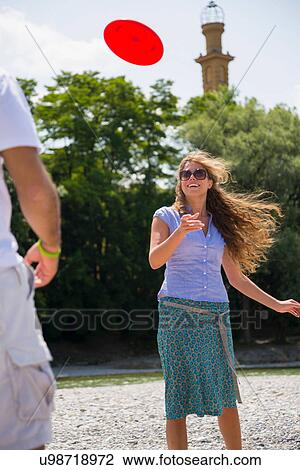 Stock Image - Mid adult couple playing with flying disc. Fotosearch