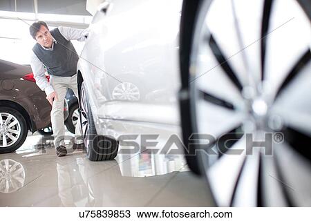 Mid adult man checking car in showroom View Large Photo Image Stock Image - Mid adult man checking car in showroom. Fotosearch