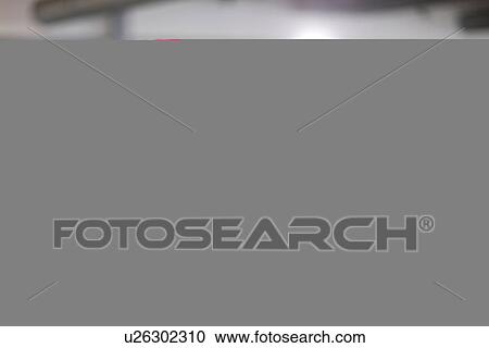 Stock Image - Mid adult man looking at car bonnet in showroom. Fotosearch