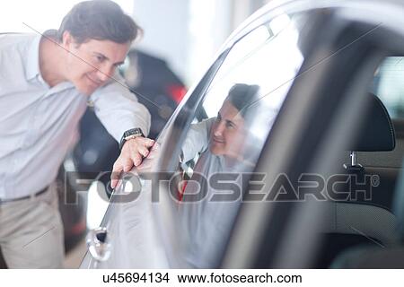 Mid adult man looking at car in showroom View Large Photo Image Picture - Mid adult man looking at car in showroom. Fotosearch