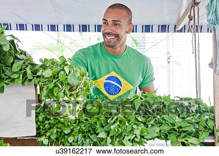 Stock Photo - Mid adult man selling fresh produce in market. Fotosearch