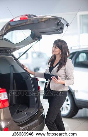 Mid adult woman checking car boot in showroom View Large Photo Image Stock Photograph - Mid adult woman checking car boot in showroom. Fotosearch