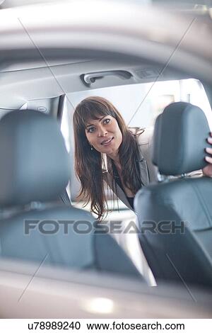 Stock Image - Mid adult woman checking car seat in showroom. Fotosearch