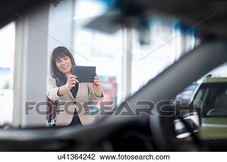 Mid adult woman photographing car in showroom View Large Photo Image Stock Image - Mid adult woman photographing car in showroom. Fotosearch