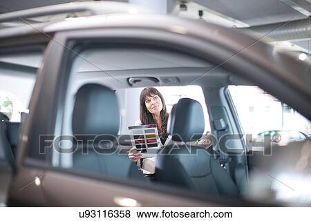 Mid adult woman with color swatch in car showroom View Large Photo Image Stock Photo - Mid adult woman with color swatch in car showroom. Fotosearch
