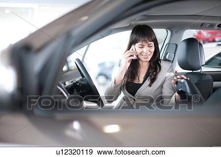 Mid adult woman with mobile phone in car showroom View Large Photo Image Stock Photo - Mid adult woman with mobile phone in car showroom. Fotosearch