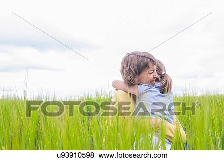 Mother and daughter hugging in field View Large Photo Image Stock Photo - Mother and daughter hugging in field. Fotosearch