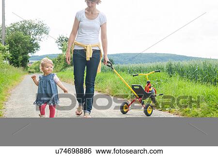 Stock Photograph - Mother and daughter walking down country road. Fotosearch