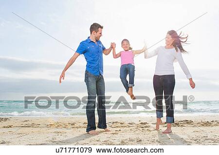 Mother and parents swinging girl on beach View Large Photo Image Stock Photo - Mother and parents swinging girl on beach. Fotosearch