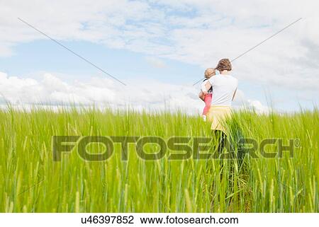 Stock Image - Mother holding daughter in field. Fotosearch