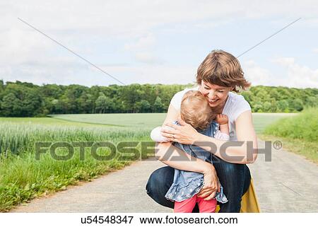 Mother hugging daughter on country road View Large Photo Image Stock Photo - Mother hugging daughter on country road. Fotosearch