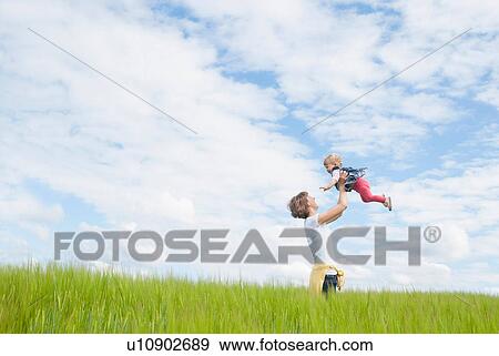 Mother lifting daughter in field View Large Photo Image Stock Photo - Mother lifting daughter in field. Fotosearch