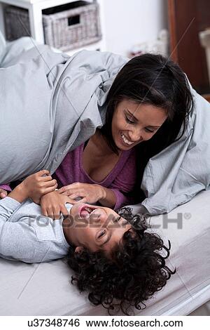 Mother tickling son on bed View Large Photo Image Stock Photograph - Mother tickling son on bed. Fotosearch