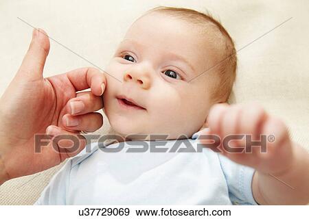 Stock Photo - Mother touching baby boy's cheek. Fotosearch